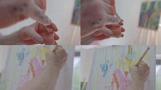 老画家的手用刷子画笔，在画布上画笔。
