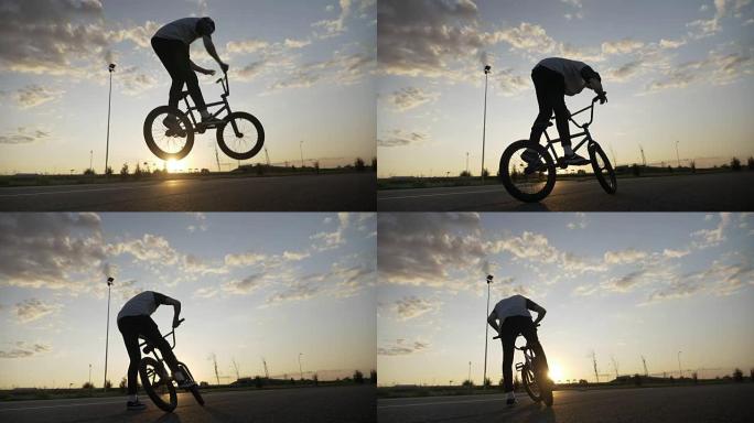 专业的年轻骑自行车的人跳上他的自行车在半空中旋转车把在日落时锻炼奥利把戏