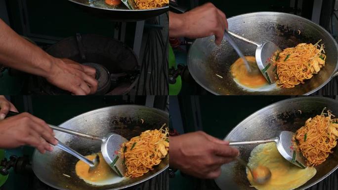 男子在泰国美食街市场煮泰国面条配鸡蛋