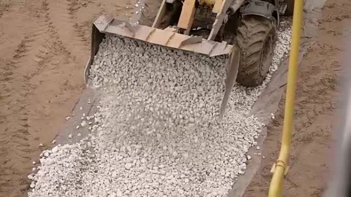 在金属钢包上近距离射击，重型机械在道路上卸下小石头，鹅卵石，然后将沥青放在那里