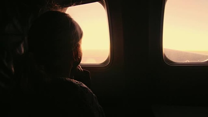 女孩坐在飞机上，看着窗外升起的太阳