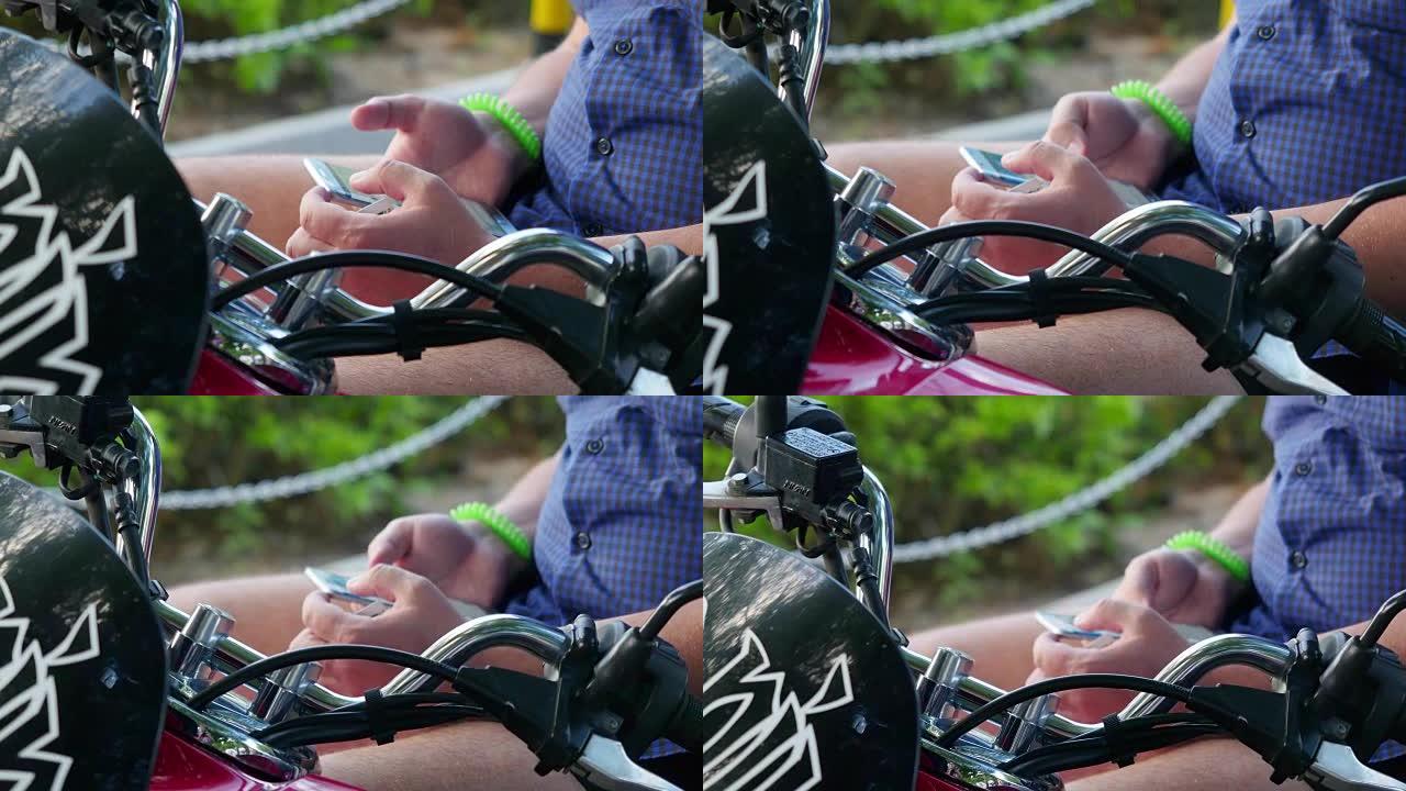 男人坐在复古摩托车上，在公园里使用手机，时髦的概念。双手合十。3840x2160