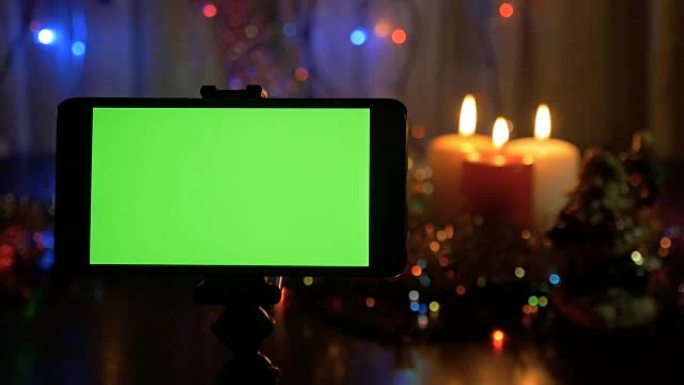 绿屏智能手机。新年背景模糊。一个很好的机会来添加你的问候视频。