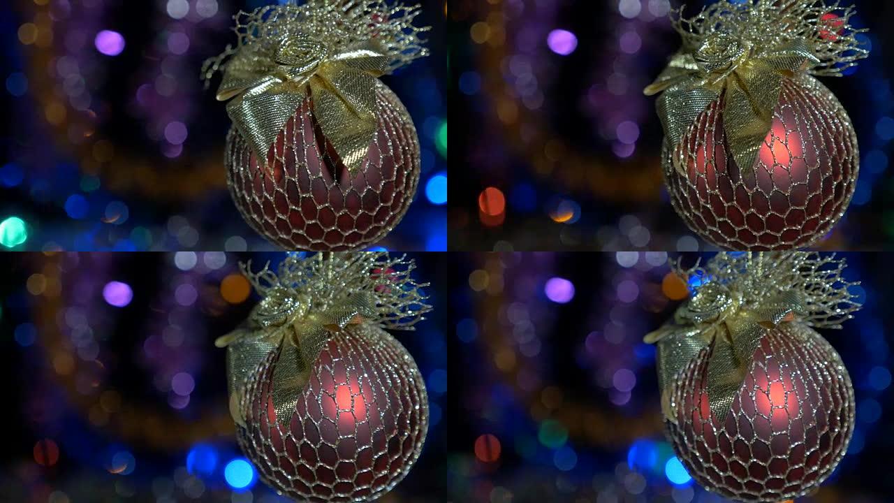 一个美丽的红球。新年和圣诞装饰品。燃烧蜡烛。闪光花环。背景模糊。