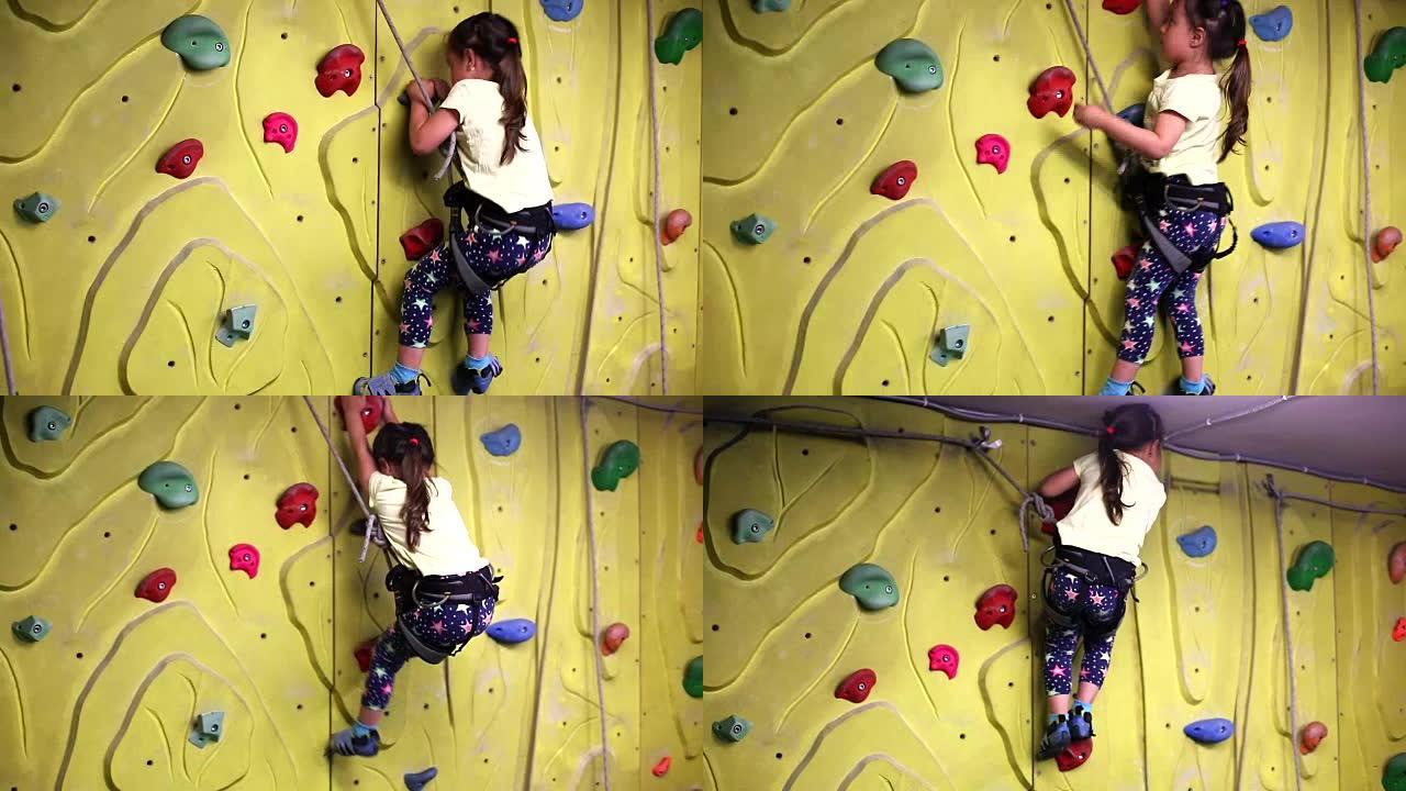年轻女孩爬上室内攀岩墙