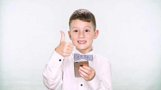 男婴显示拇指朝下，并在白色背景上玩平板电脑或智能手机