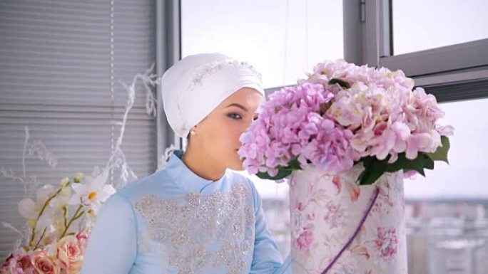美丽的穆斯林新娘穿着漂亮的婚纱，闻着花