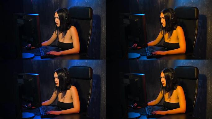 严肃的女性玩家在电脑上玩网络游戏，戴着耳机，用麦克风与团队交谈