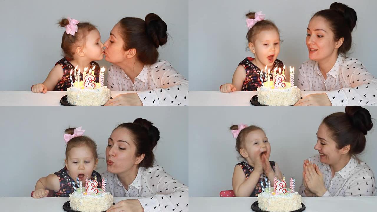 快乐的妈妈和孩子在聚会上吹灭生日蛋糕上的蜡烛。母亲祝贺、拥抱和亲吻她的女儿。3年
