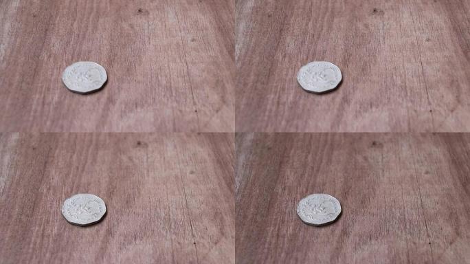 在木地板上旋转五泰铢，呈古代泰国货币的形状，并以鹰航形式的硬币反向停止。