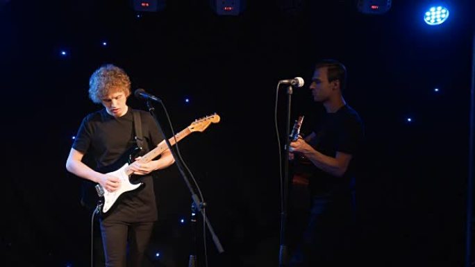音乐会摇滚乐队与两位电吉他歌手一起在舞台上表演。音乐录影带庞克、重金属或摇滚乐团。两个男人的慢动作乐