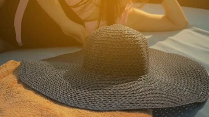 美丽的女孩正戴上蓝色的帽子，躺在躺椅上。夏日的阳光。慢动作。