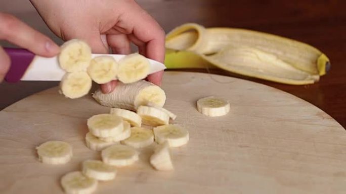 女人在砧板上切香蕉的特写。
