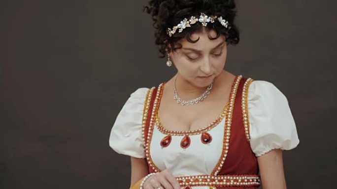 美丽的女人站在工作室的黑色背景上的18世纪古老的皇家服装中。玛丽·安托瓦内特在舞会上的样子。服装细节