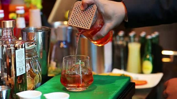 调酒师在酒吧将鸡尾酒与酒杯混合，将酒保手倒入酒杯中