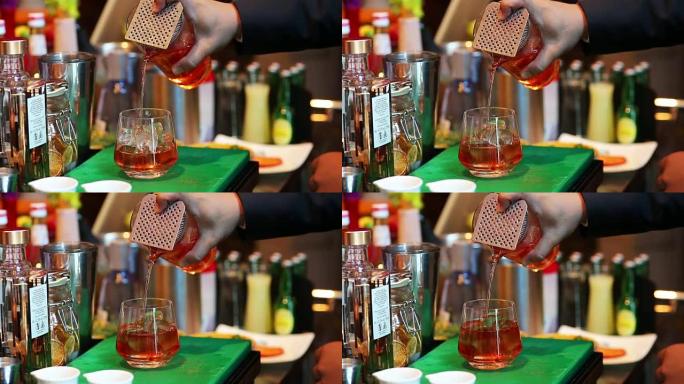 调酒师在酒吧将鸡尾酒与酒杯混合，将酒保手倒入酒杯中