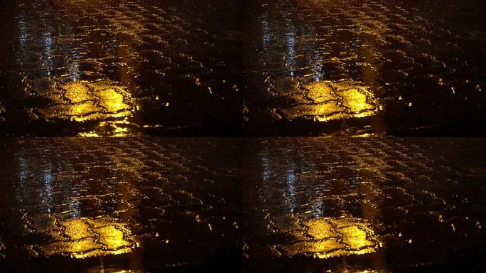 夜街上下雨。水坑中的黄色路灯反射。