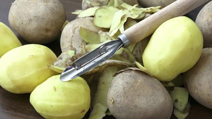 Raw potatoes and knife on a wooden background