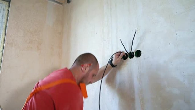 电工在墙内铺设布线电缆线。