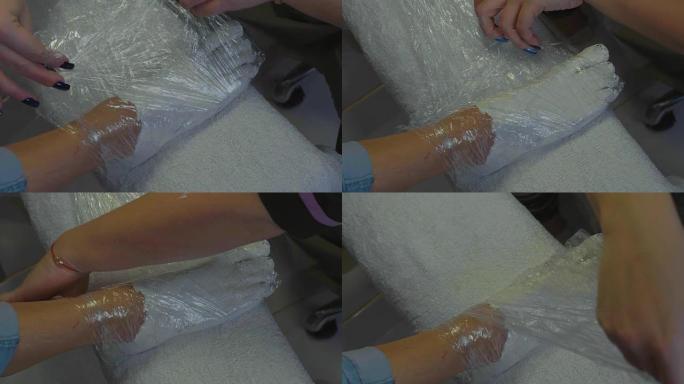 Beautician wrapping customer's feet with cream at 