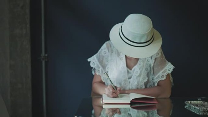 戴着白帽子，穿着复古白色连衣裙的亚洲艺术家正在为周末的休闲活动写作和素描