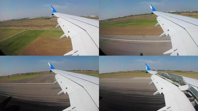 从飞机机翼上的窗户看，飞机低空飞到地面并降落在机场