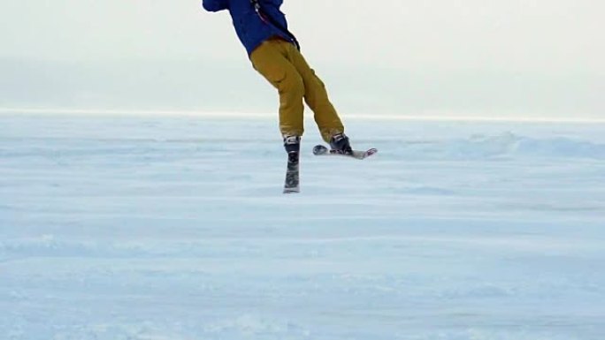 慢动作:一名男运动员正在滑雪板上放风筝。他在一个大湖的冰面上打滚。翻滚时，他会进行各种跳跃、动作和其