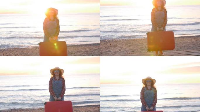 日落时在海滩上带着手提箱的年轻女子旅行者