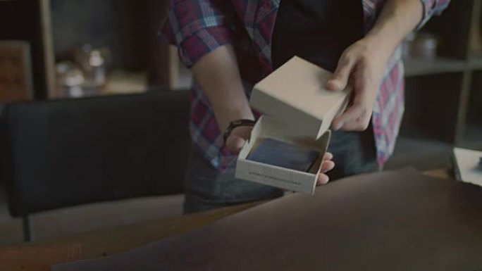 工人将皮革钱包放在小商店的产品包装盒中