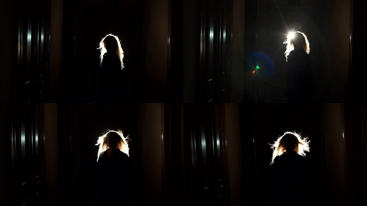 黑暗中头发飘动的女孩的剪影。