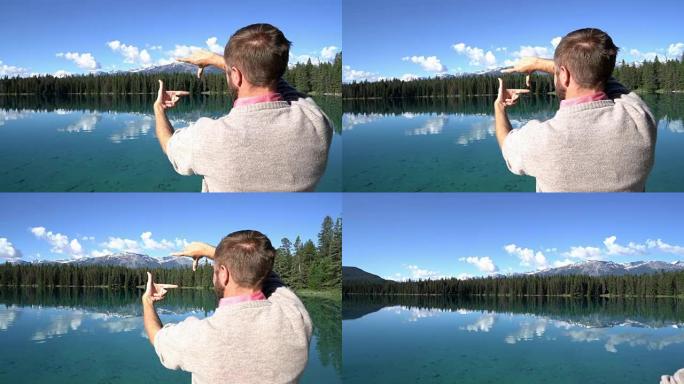 男子站在令人惊叹的湖面上方的木墩上，用手做框架