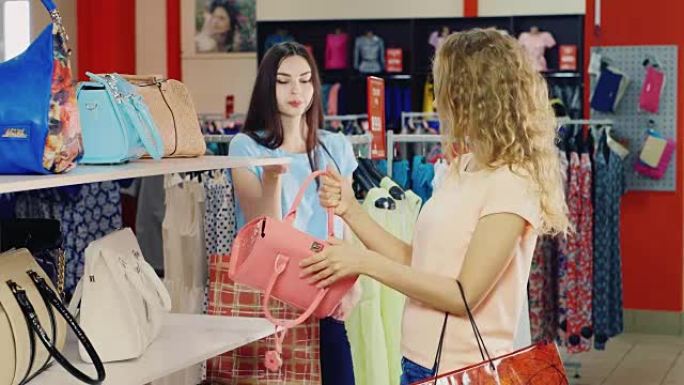 两位女友在店内挑选手袋，讨论即将购买