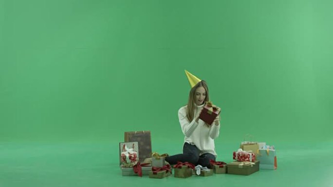 迷人的年轻女子看着她的圣诞礼物和购物袋，背景上的色键