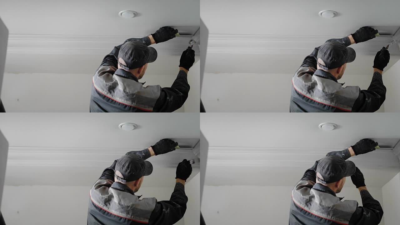 该名男子正在公寓中进行维修，该人正在用流苏石膏在天花板上涂漆