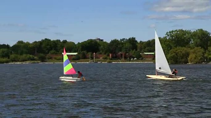 当帆船学校的学生进行演习时，两艘小船在开阔的水面上来回穿梭。
