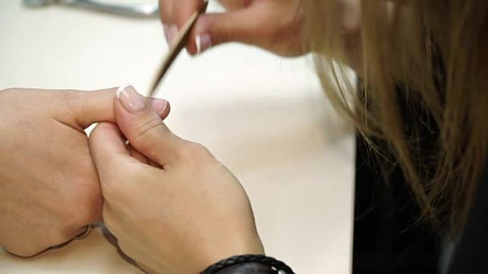 一个女人在美甲沙龙接受美容师用指甲锉修指甲的特写镜头。正在修指甲的女人。美容师向客户钉钉子