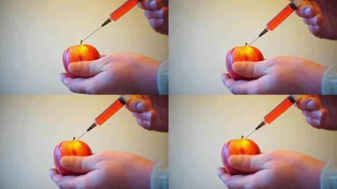 男性双手用注射器注射到成熟的苹果中