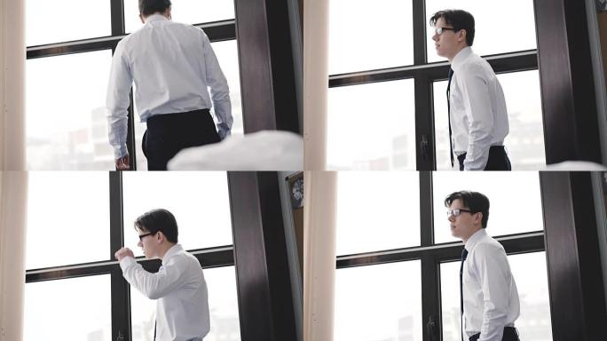 Handsome businessman waiting at windows in office.