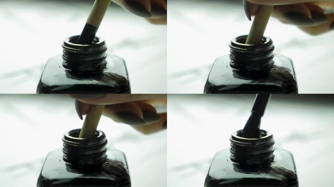 女性手将刷子浸入一罐墨水中，以绘制特写。具有选择性焦点的中国老式油漆刷。中国画笔的细节，同时在光线中