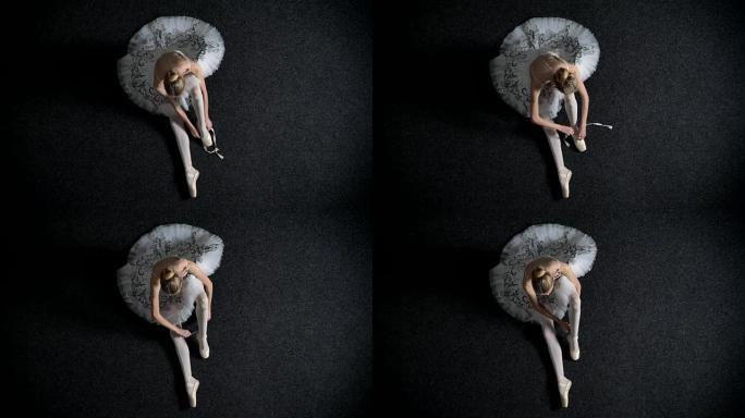 年轻女孩芭蕾舞演员的轮廓放在足尖上，坐在地板上，芭蕾舞概念，顶拍