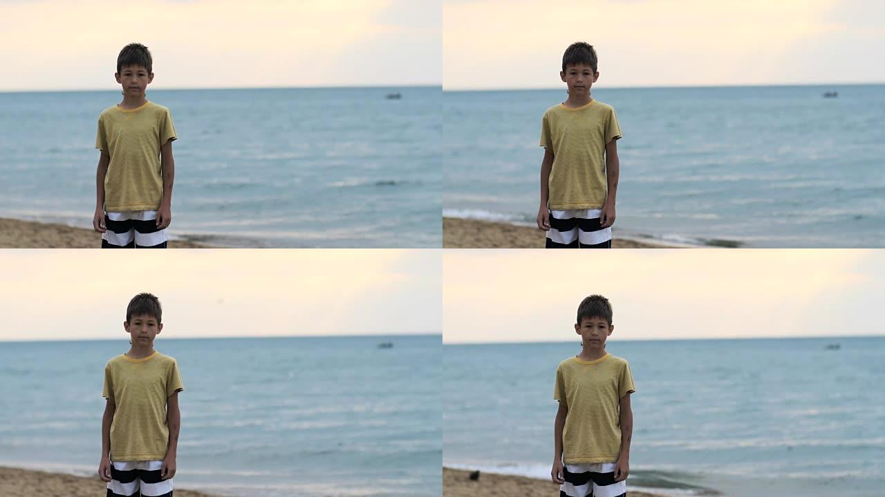 男孩站在海边的海滩上，看着相机