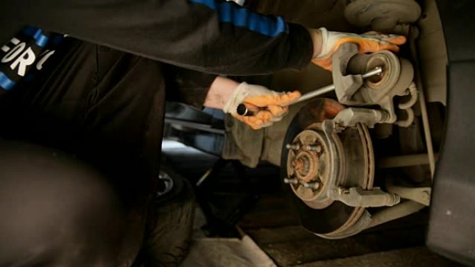 汽车修理工在汽车修理厂国内车库里做刹车。
