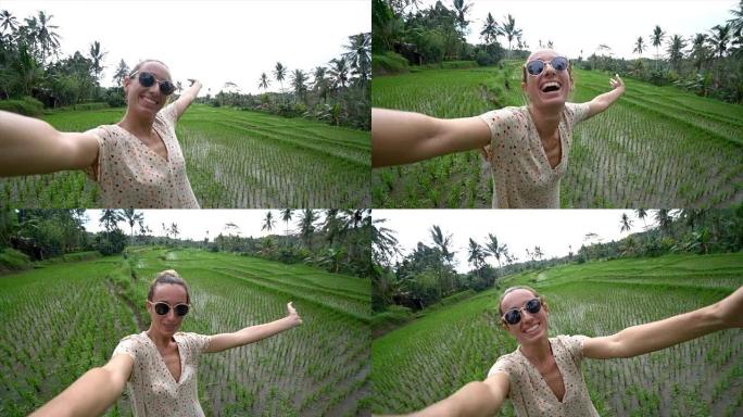 在亚洲旅行的年轻女子在印度尼西亚巴厘岛的稻田露台附近用相机自拍。游客采取自拍照的观点