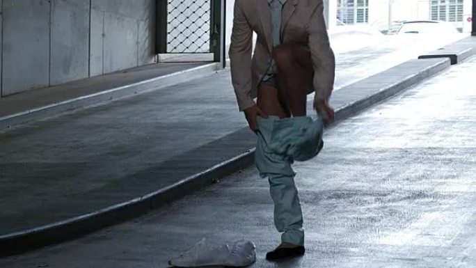 男舞者在停车场的坡道上脱衣服