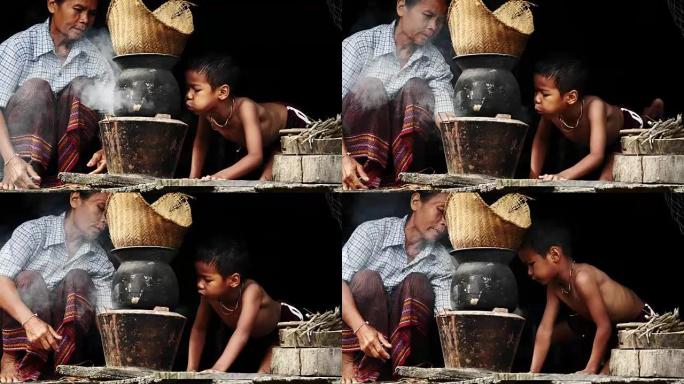妈妈和孩子在泰国农村早上吹炭炉煮饭。(手持相机)