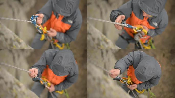 挂在绳子上的攀岩者的特写镜头，解开卡宾枪和保险