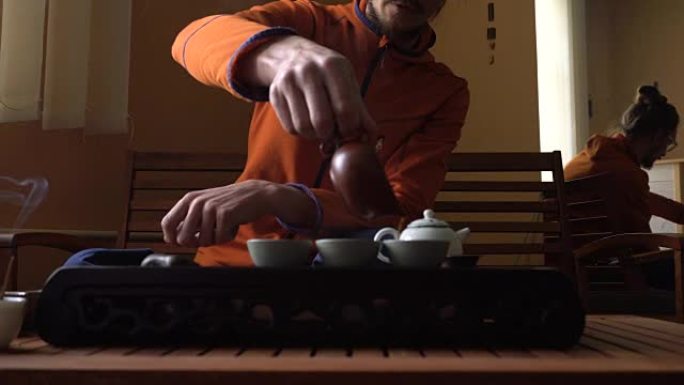 在中国传统茶道上，戴眼镜的人在茶壶里倒普洱茶。一套饮茶设备