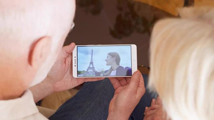 在家中的高级夫妇与来自巴黎的学生女儿进行视频聊天，背景是埃菲尔铁塔
