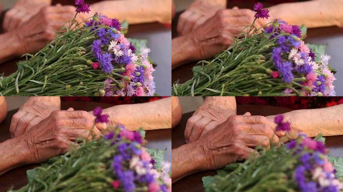 一束鲜花和起皱的手的特写