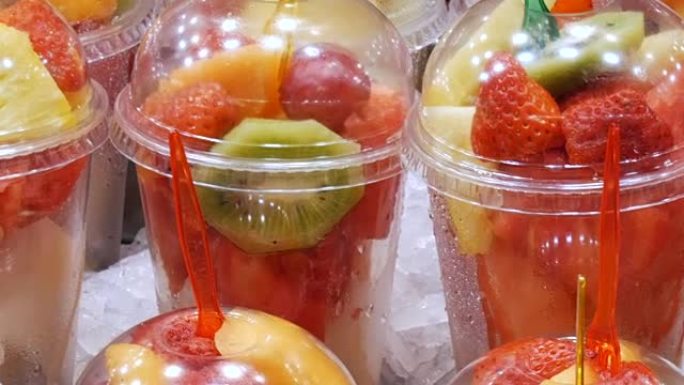 新鲜刚包装在塑料杯混合水果西瓜，猕猴桃，梨，苹果，草莓特写视图